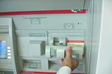 ATM skimmer device being installed on front of existing bank card slot